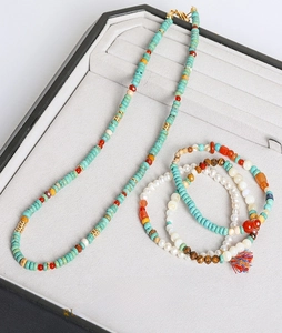 Detail view of turquoise beaded necklace and pearl bracelets with colorful tassels