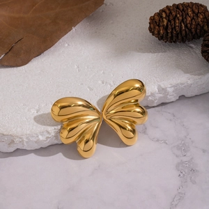 Detail of 18K gold butterfly wing earrings with polished ribbed texture on a stone plate