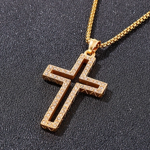 Macro detail of gold plated hollow cross pendant featuring set rhinestones and box chain
