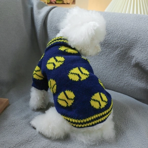 Detail of navy blue dog sweater with yellow tennis patterns on a white Bichon dog
