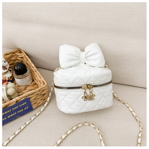 Detailed macro view of a white quilted crossbody bag with a large ribbon bow and floral zipper