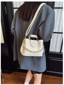 Detail of cream bucket bag featuring gold chain and Fashion & Bags text on textured leather