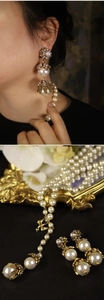 Dettaglio di orecchini pendenti con perle barocche e collana floreale color oro antico