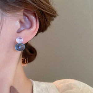 Close-up of blue and clear resin gourd stud earrings worn on model for delicate style