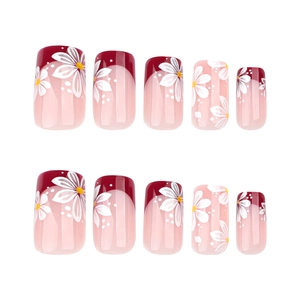 Short square press-on nails with red French tips and delicate white flower patterns