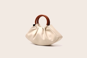 Detail view of beige ruched dumpling bag featuring premium dark brown wooden circular handles