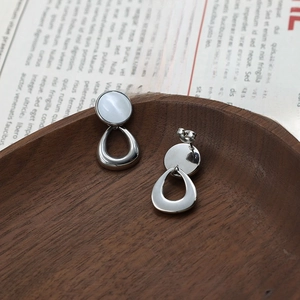 Elegant geometric silver drop earrings with white cat eye stones on a vintage background