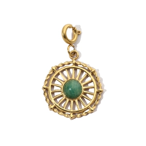 Dettaglio di un ciondolo dorato con pietra verde centrale e design traforato a raggiera