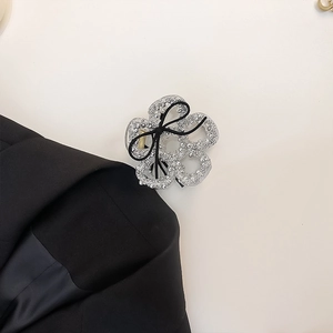 Detail of silver rhinestone flower hair claw with elegant black ribbon bow accessory