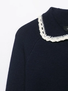 Detail of navy knit sweater featuring contrast white crochet collar with scalloped edges