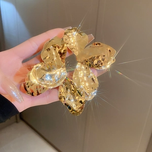 Detailed view of large golden irregular metal flower petal hair accessory with textures