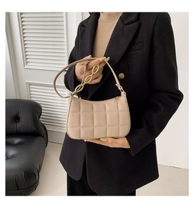 Detailansicht der beigen gesteppten Baguette-Tasche mit goldener Kette und Reißverschluss