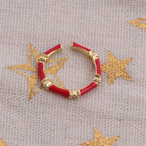 Bamboo-style open ring in gold metal with red enamel and zircon detail on linen background