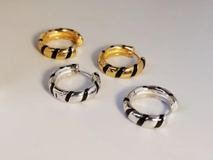 Detailed view of S925 silver hoop earrings with black enamel zebra stripes and gold finish