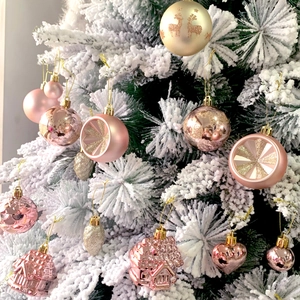 Close-up of pink and gold Christmas ball ornaments and heart pendants on a snow-covered tree