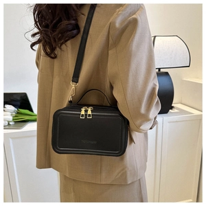 Detail of a chic black leather crossbody bag with gold zippers and adjustable strap