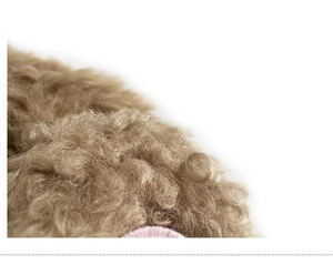 Detailed macro view of the curly brown plush fabric with fine pink embroidery accents