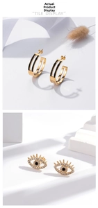 Détail des boucles d'oreilles C dorées avec zircons noirs et clous Oeil du Diable