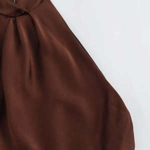 Close-up of brown satin midi dress showing elegant fabric pleats and drape texture