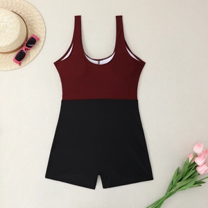 Flat lay of a two-tone one-piece swimsuit with sunglasses and summer hat detail