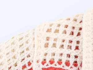 Macro shot of beige and red crochet hollow knit fabric with detailed stitch texture