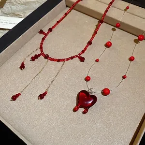 Red beaded fringe necklace and transparent cord choker with heart-shaped resin pendant