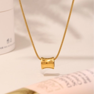 Elegante gouden cilindrische hanger halsketting met fijne slangenketting op witte basis