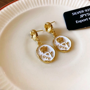 Vintage style gold earrings with white enamel oval drop and golden rose relief