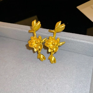 Macro detail of vintage gold lotus earrings with matte finish on grey velvet stand