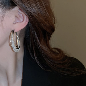 Detail of silver double hoop earrings with textured inner layer and polished outer finish