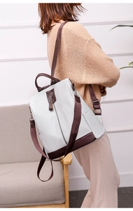 Detail of color-block PU leather backpack showing anti-theft back zipper and side pockets