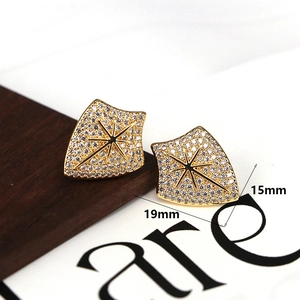 Macro shot of gold shield-shaped stud earrings with star motif and cubic zirconia