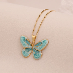 Vintage gold butterfly pendant necklace with teal enamel inlay on a minimal gold chain