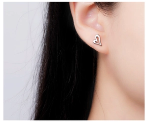 Detailed close-up showing the hollow heart earring on a model's ear in silver finish