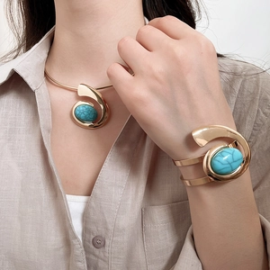 Close-up of gold choker necklace and layered bracelet set with turquoise resin gemstones