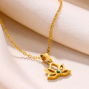 Macro shot of 18K gold lotus flower pendant with a green zircon stone on white silk