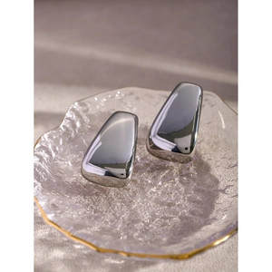 Boucles d'oreilles trapézoïdales argentées polies sur un plateau en verre décoratif