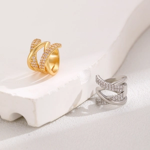 Detail of gold and silver double-layered X-cross ear cuffs set with sparkling zircons