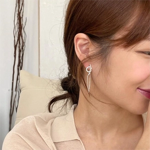 Close-up shot of a minimalist 925 sterling silver knotted long tassel earring on model