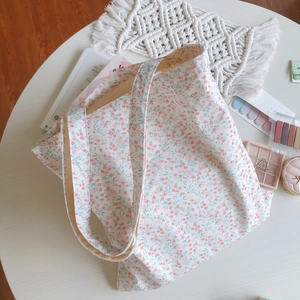 Floral canvas tote bag with pink blossoms on a white desk for casual lifestyle use