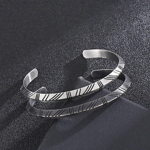 Detailed close-up of men's titanium steel cuff with geometric V-shaped textures
