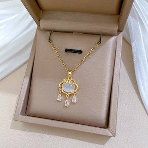Close-up of gold Ruyi lock necklace with white opal stone and hanging crystals
