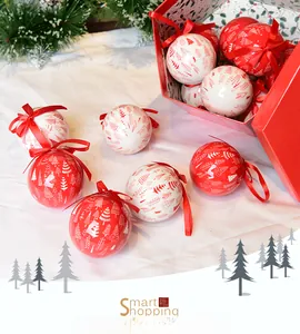 Detail of red and white Christmas tree ornaments with festive patterns and ribbon in a gift box