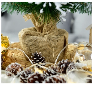 Close-up of a 60cm mini Christmas tree with artificial snow and burlap base on a table