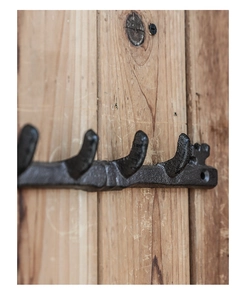 Close-up detail of vintage black cast iron coat hook on rustic wooden surface