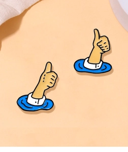Detail view of two cute cartoon thumb up enamel pins with blue water waves on orange background