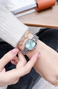 Detail shot of an elegant silver watch with a mint green dial and metallic beaded bracelet
