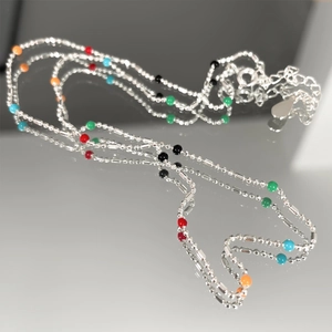Macro shot of S925 sterling silver chain with vibrant colorful beads on a reflective surface