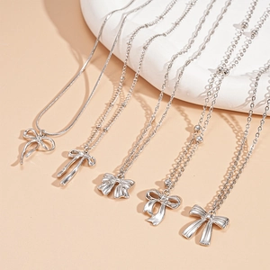 Détail d'un ensemble de cinq colliers argentés avec divers pendentifs en forme de nœud