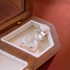 Macro detail of silver leaf earrings with cubic zirconia in a wooden jewelry box